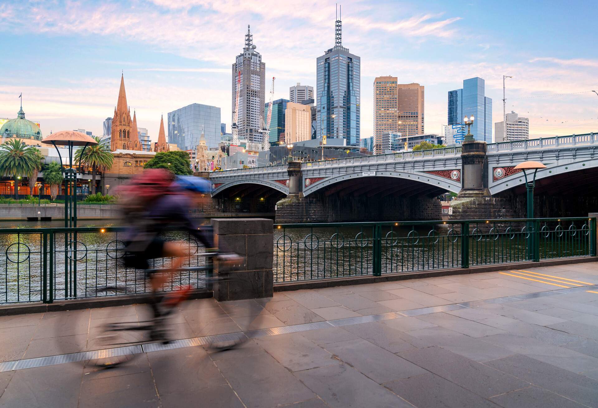 Australian people cycling for exercise near Yarra River with view of the Melbourne City Financial District with skyscrapers in morning at Melbourne, Victoria, Australia.