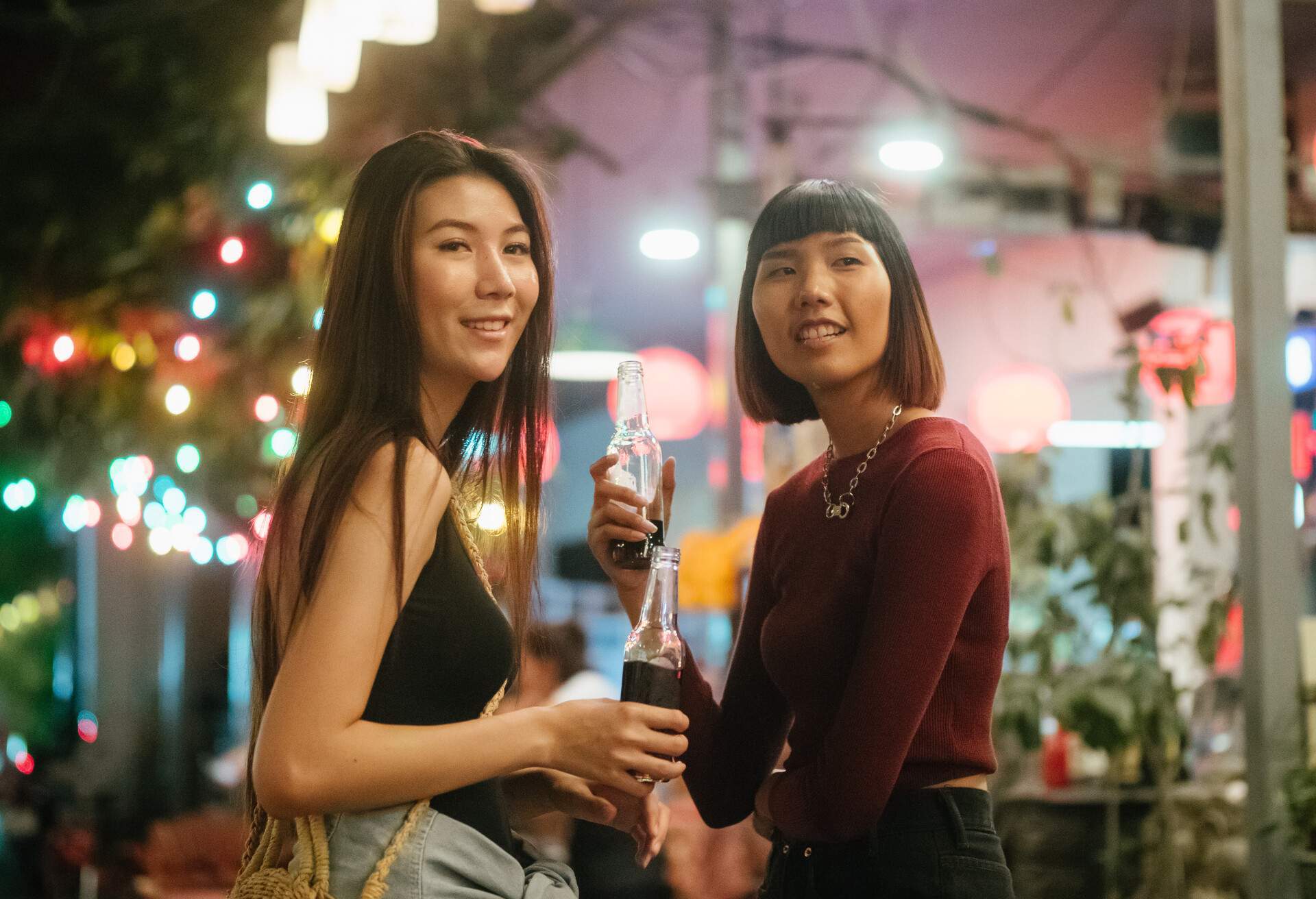 Happy asian friends travelers enjoying and drinking beer at night market. Bangkok, Thailand. 