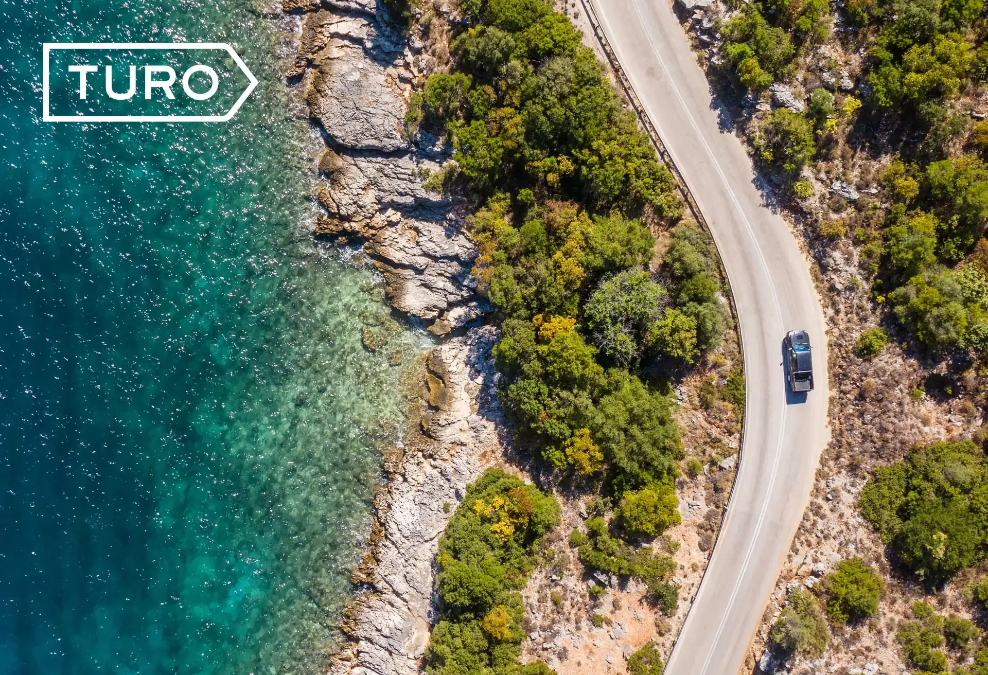 Scenic coastal drive with Turo – winding road, clear waters, and lush greenery.
