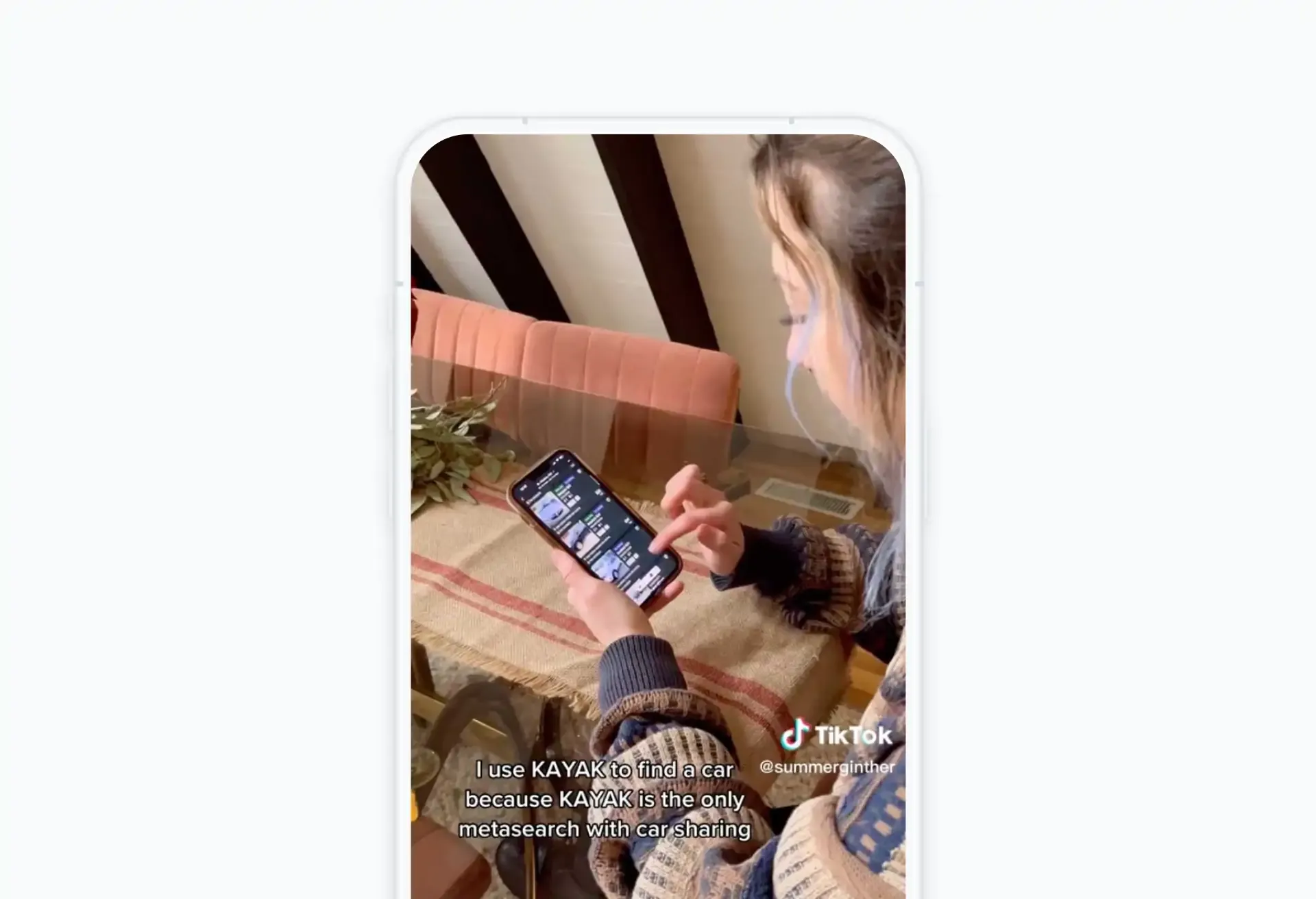 Young woman browsing travel content on her phone in a cozy setting.