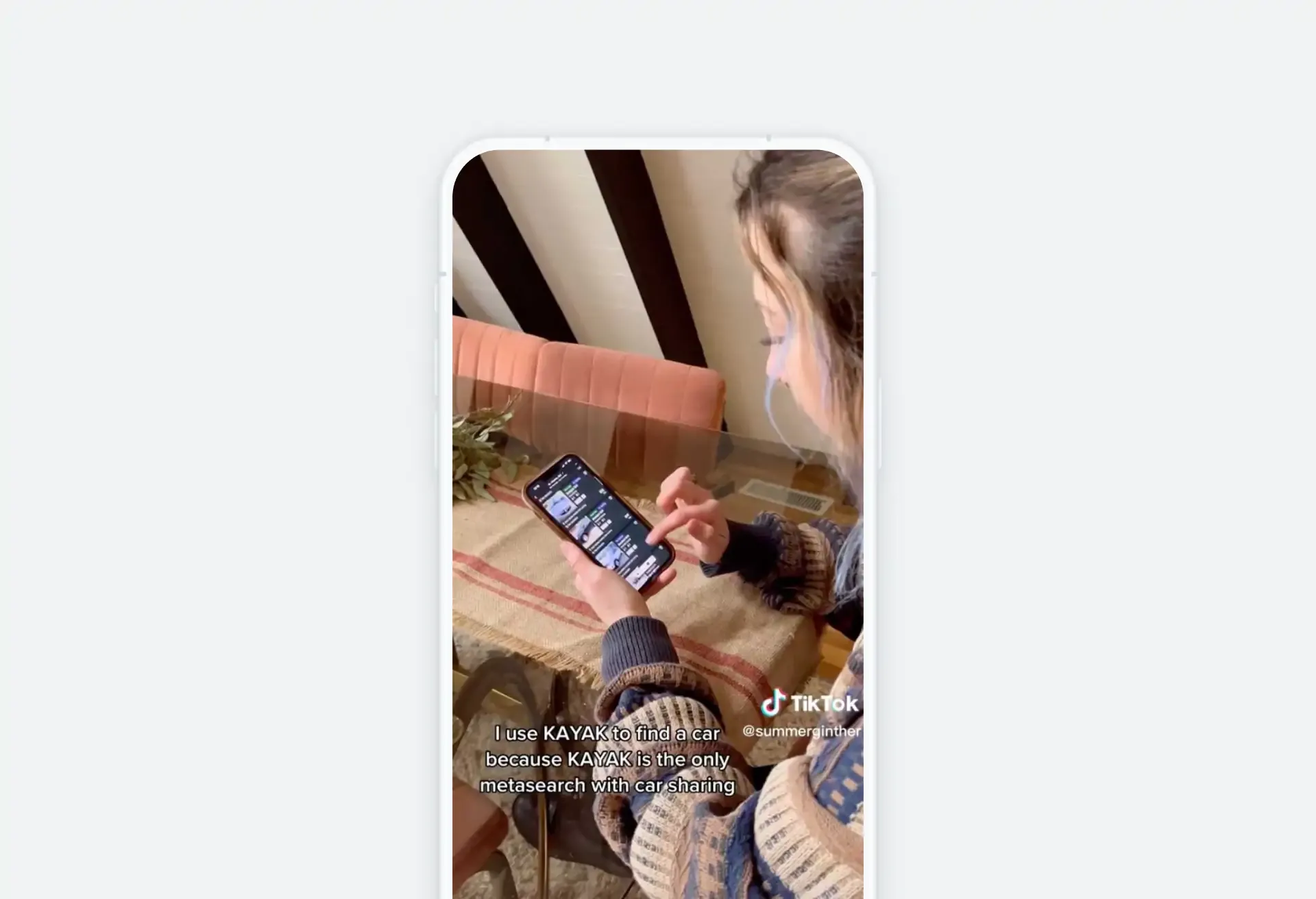 Woman scrolling travel content on her phone in a cozy indoor setting.