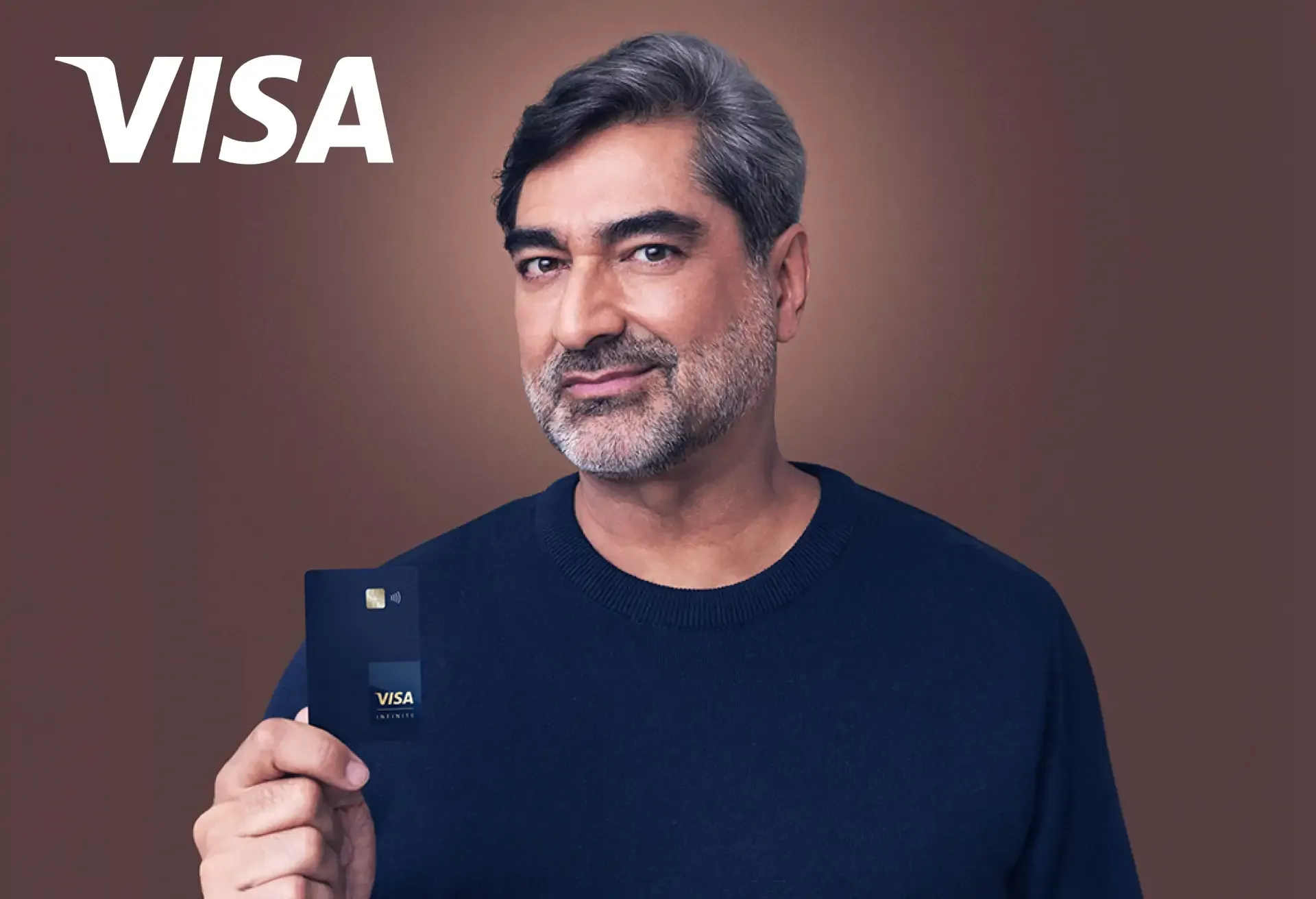 Confident man holding a sleek Visa Infinite card against a stylish brown background.