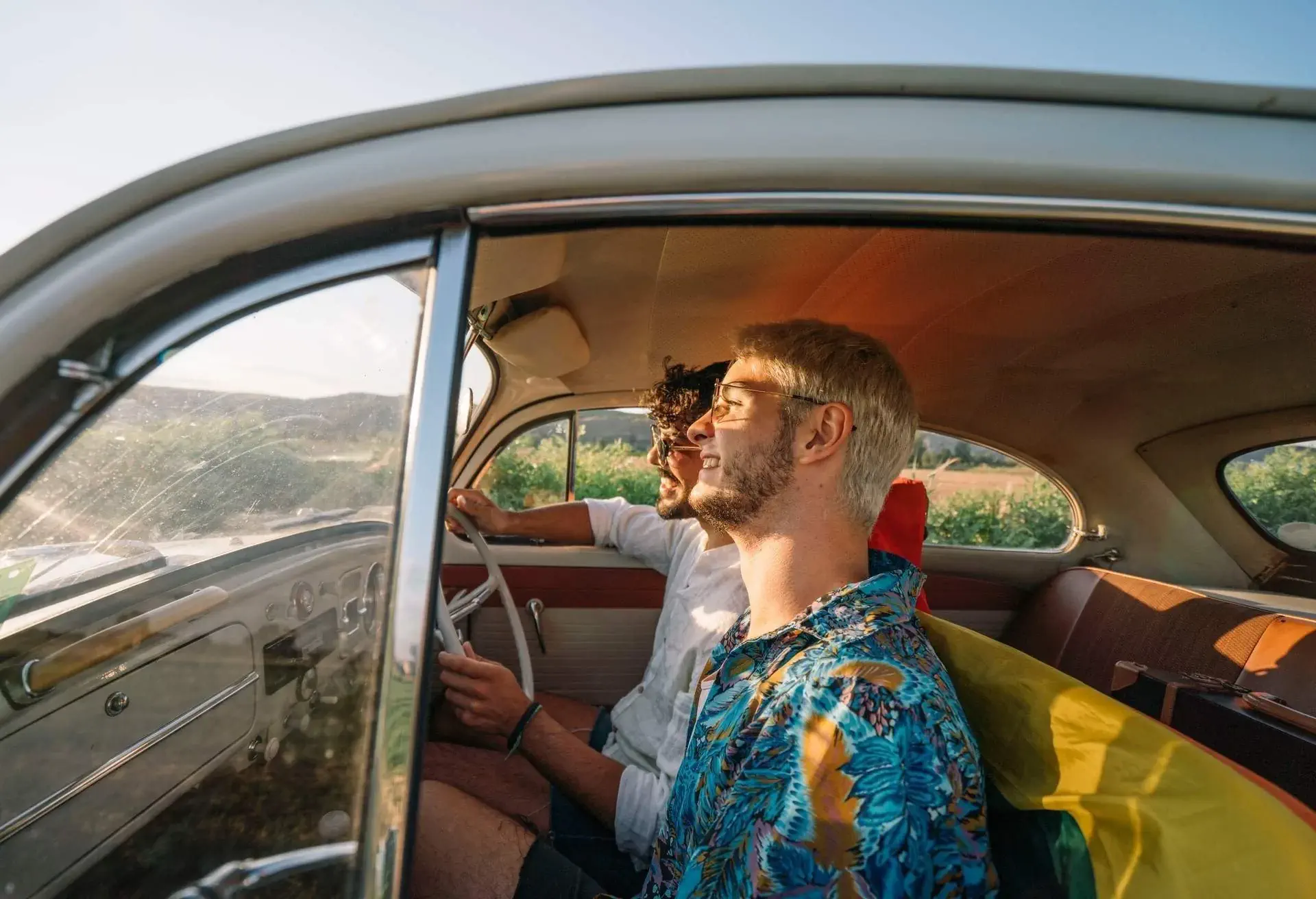 Two friends riding in the front seats of a vintage car.