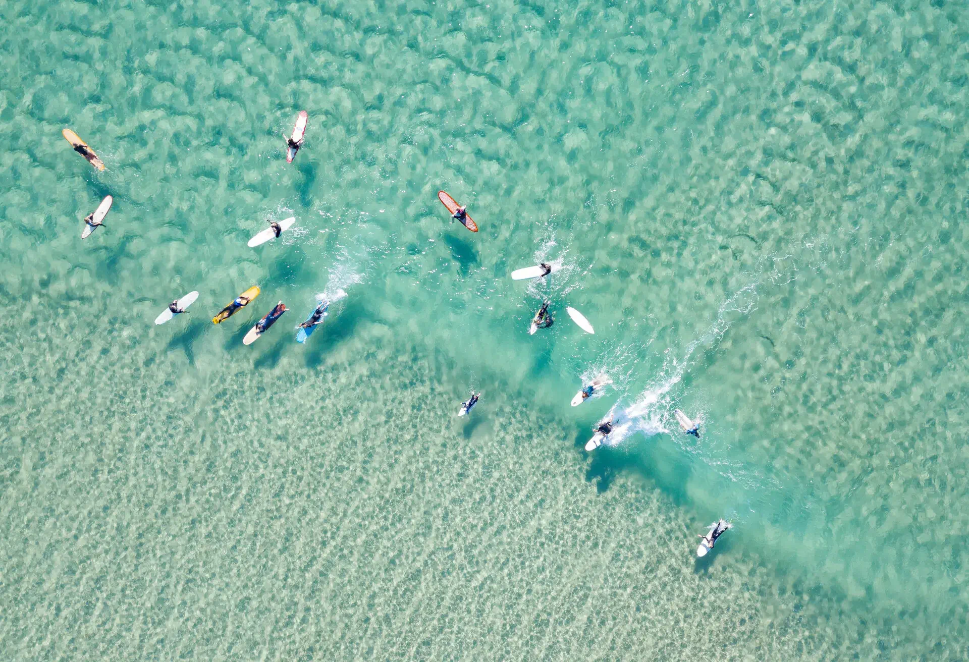 looking down on crystal clear waters with surfers coastline Australia