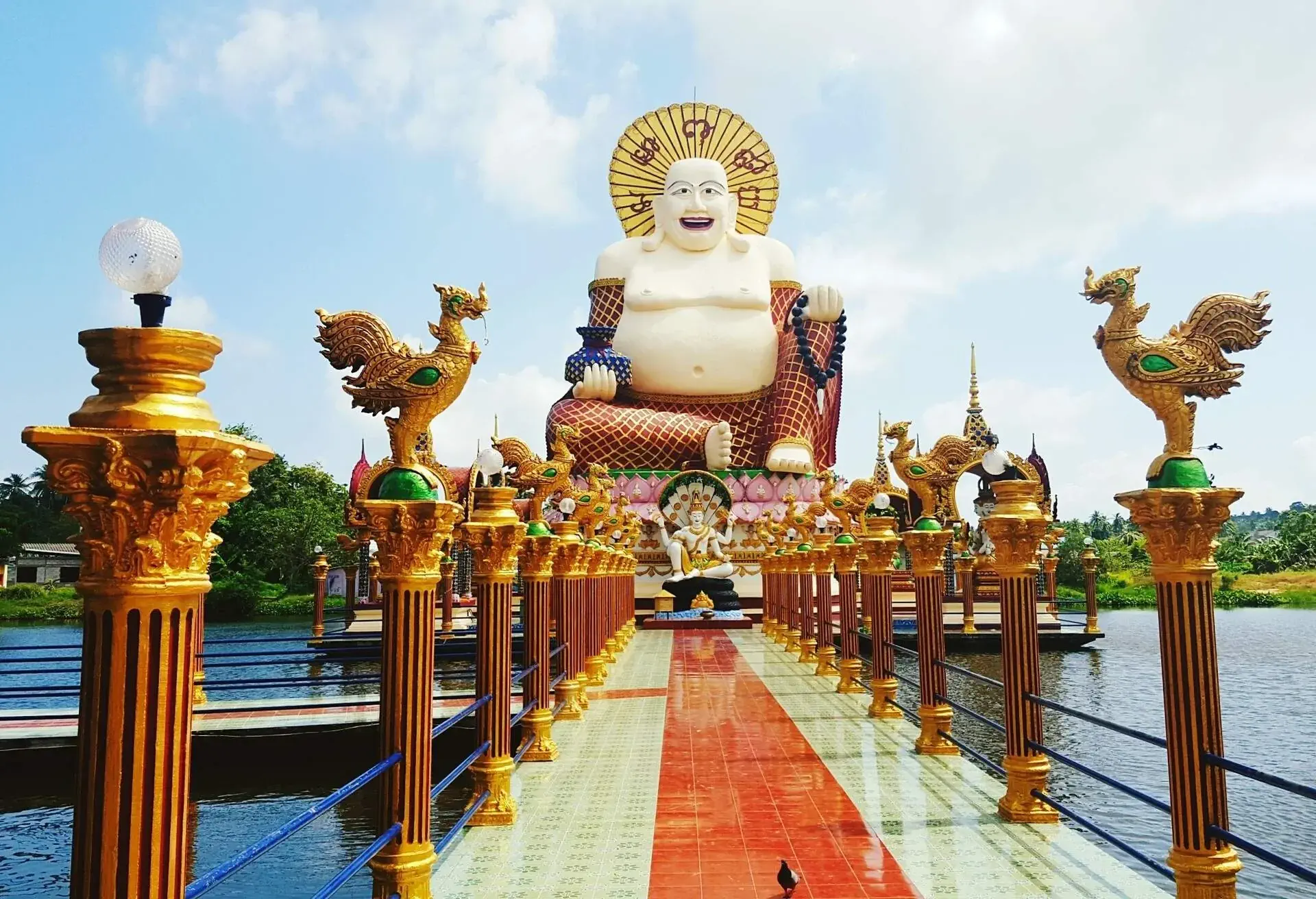 Low Angle View Of Buddha Statue Amidst Pond In Temple Against Sky