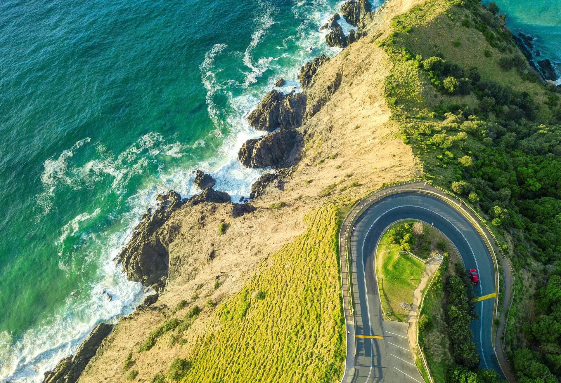 looking down on the Australian coastline with rocky outcrop and windy road