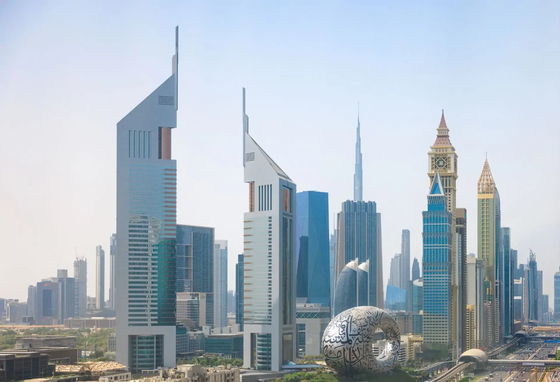 Modern skyline of Dubai showcasing iconic towers under a clear daytime sky.